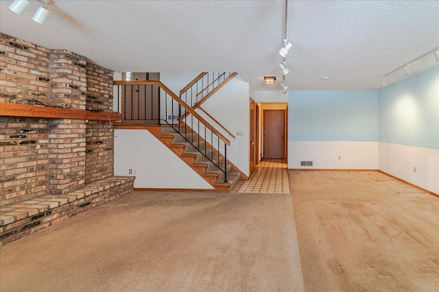 unfurnished living room featuring light carpet, track lighting, and a textured ceiling