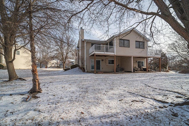 snow covered back of property featuring a wooden deck