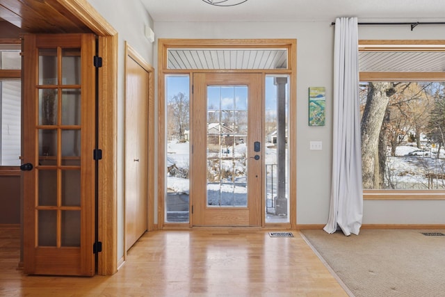 entrance foyer with plenty of natural light, baseboards, visible vents, and wood finished floors