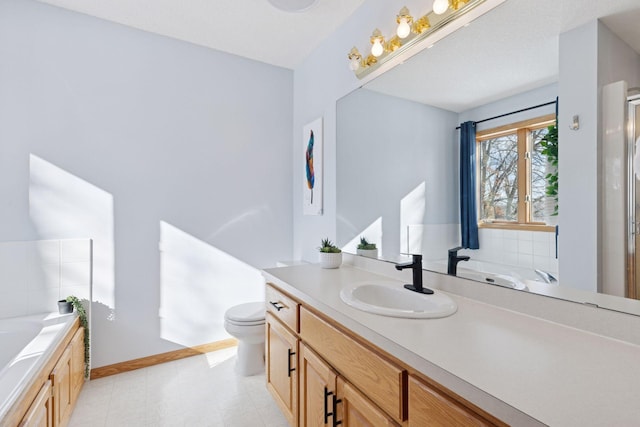 bathroom featuring vanity, toilet, a bath, and baseboards