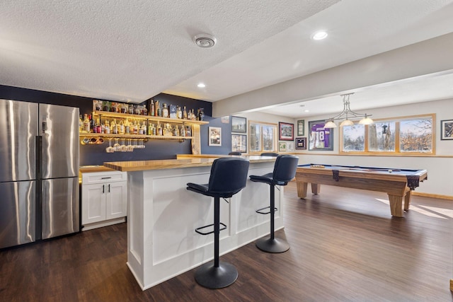 bar featuring a healthy amount of sunlight, dark wood-style flooring, freestanding refrigerator, and indoor bar