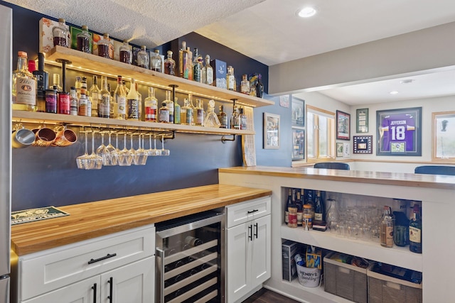 bar featuring beverage cooler, recessed lighting, and a bar