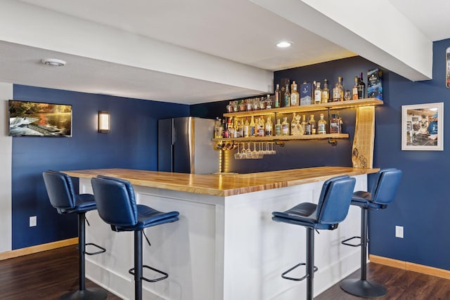 bar featuring baseboards, recessed lighting, freestanding refrigerator, dark wood-style floors, and a bar