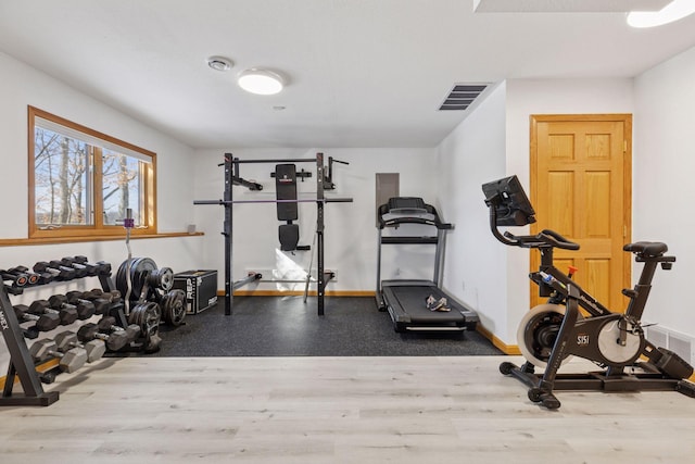 workout area featuring wood finished floors, visible vents, and baseboards