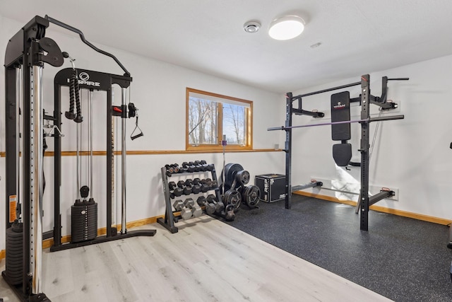 exercise room with baseboards and wood finished floors