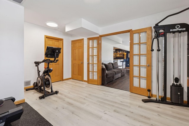 exercise area with visible vents, french doors, baseboards, and wood finished floors