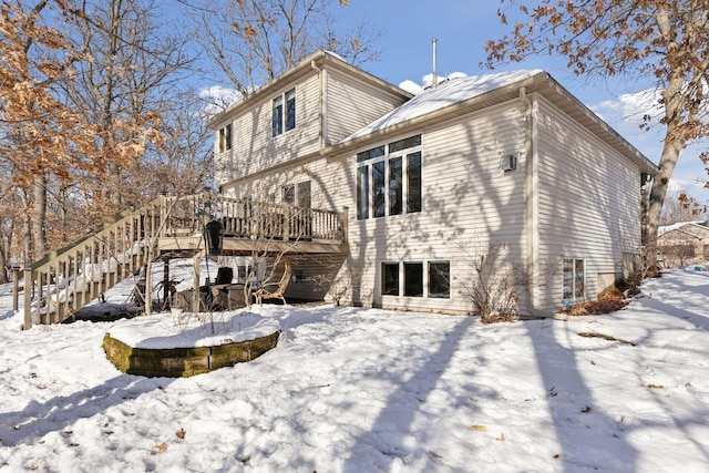 snow covered back of property featuring a wooden deck and stairs