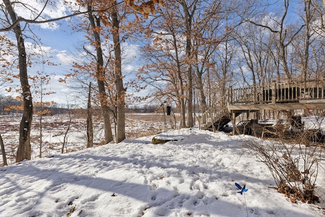 yard covered in snow featuring stairs and a wooden deck