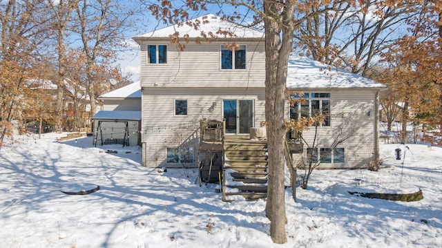 snow covered rear of property with stairway