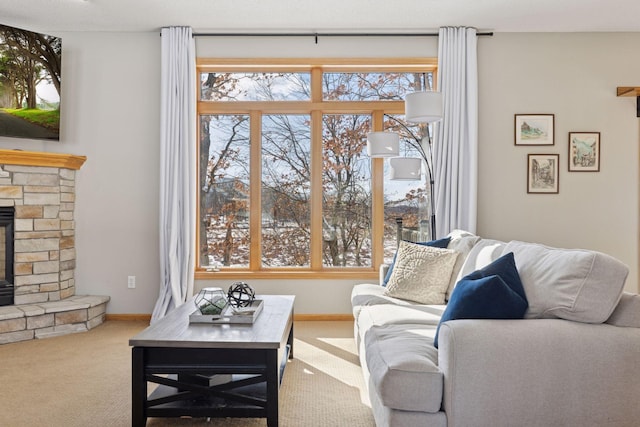 living room with baseboards, a stone fireplace, and carpet flooring