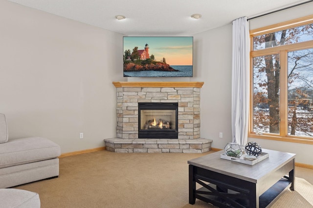 carpeted living room featuring a stone fireplace, a healthy amount of sunlight, and baseboards