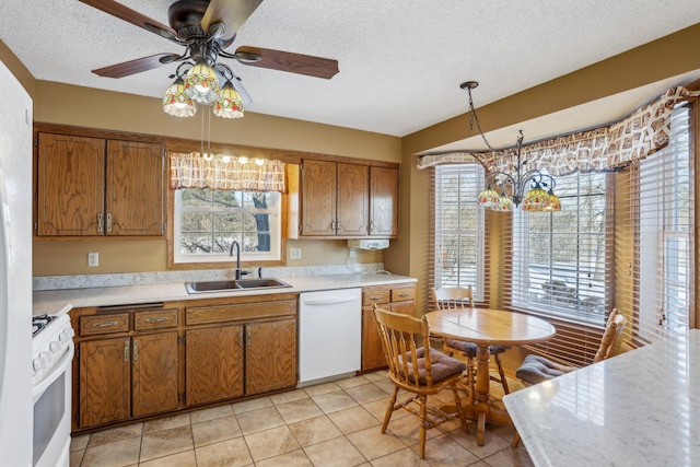 kitchen featuring pendant lighting, brown cabinets, light countertops, a sink, and white appliances