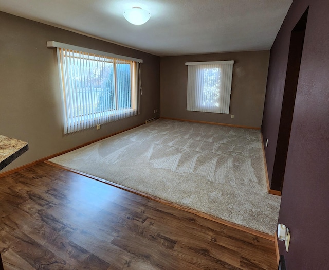 empty room with baseboards, wood finished floors, and a healthy amount of sunlight