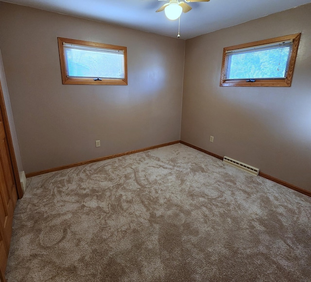 unfurnished room with carpet floors, plenty of natural light, visible vents, and baseboards