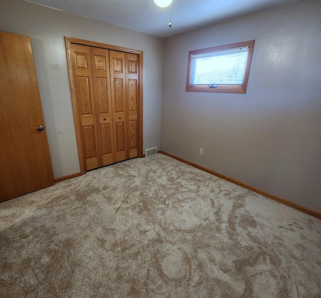 unfurnished bedroom with a closet, carpet flooring, visible vents, and baseboards