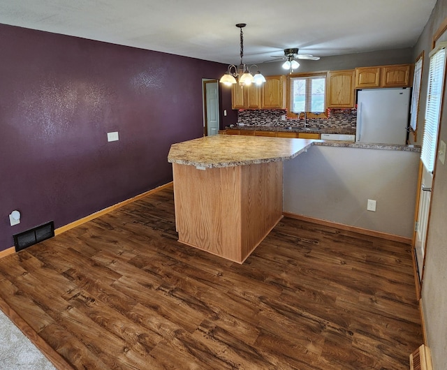 kitchen featuring a sink, dark wood finished floors, backsplash, visible vents, and freestanding refrigerator