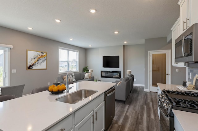 kitchen with white cabinetry, sink, dark hardwood / wood-style flooring, a kitchen island with sink, and stainless steel appliances