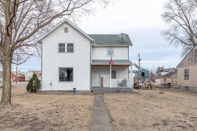 view of front of property featuring a playground, covered porch, and a front yard