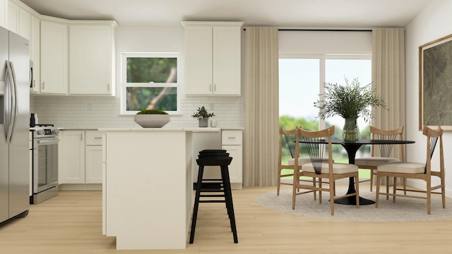 kitchen with appliances with stainless steel finishes, white cabinets, light hardwood / wood-style floors, and decorative backsplash