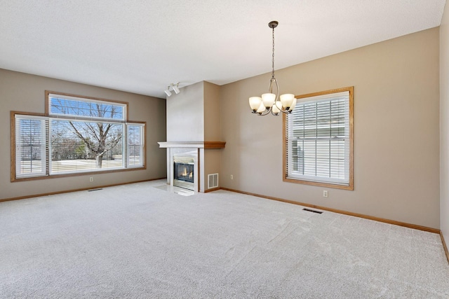 unfurnished living room with visible vents, baseboards, carpet, and a fireplace with flush hearth