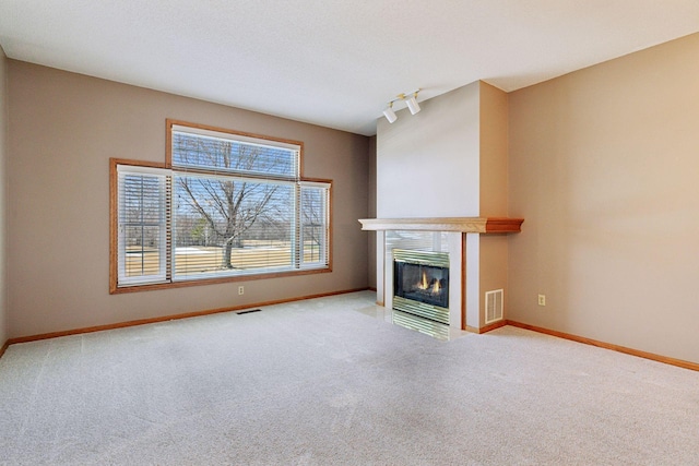 unfurnished living room featuring a tiled fireplace, visible vents, baseboards, and carpet floors