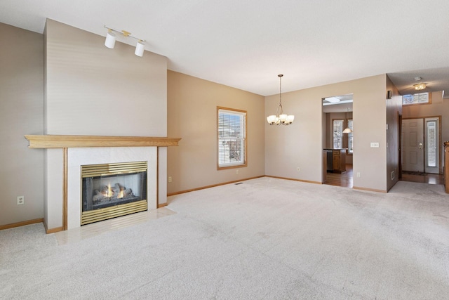 unfurnished living room featuring an inviting chandelier, a fireplace, baseboards, and carpet