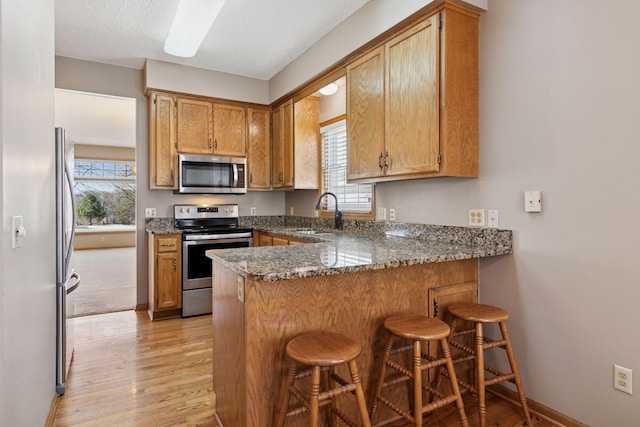 kitchen featuring a sink, plenty of natural light, appliances with stainless steel finishes, and a peninsula