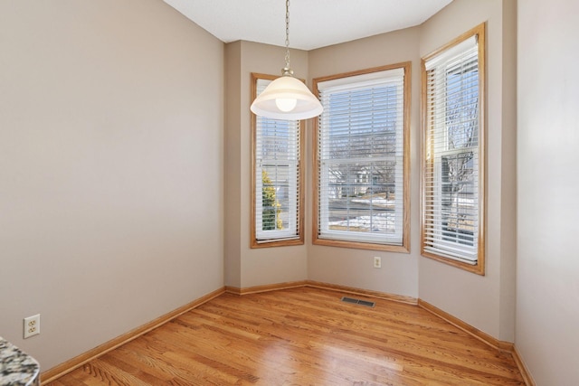 unfurnished dining area with plenty of natural light, baseboards, visible vents, and light wood-type flooring