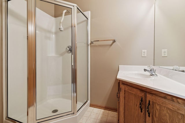 bathroom with a shower stall, vanity, and baseboards