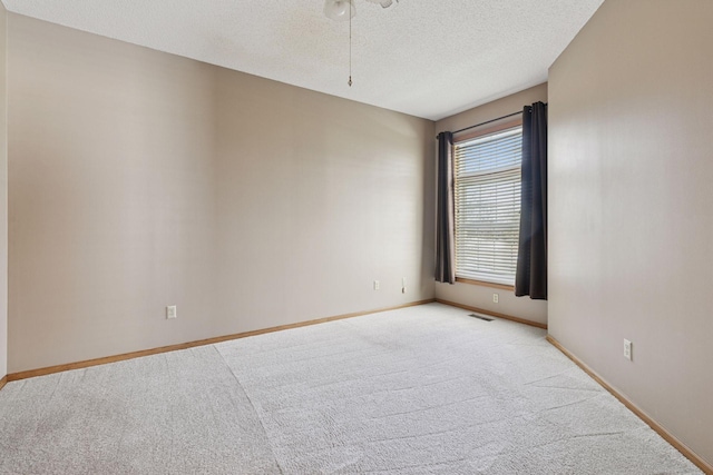 unfurnished room featuring a textured ceiling, baseboards, visible vents, and light carpet