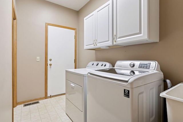 washroom featuring cabinet space, washing machine and dryer, visible vents, and a sink