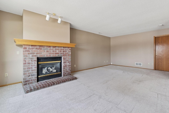 unfurnished living room with visible vents, a fireplace, a textured ceiling, and baseboards