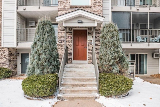 property entrance featuring a wall unit AC, a wall mounted air conditioner, and brick siding