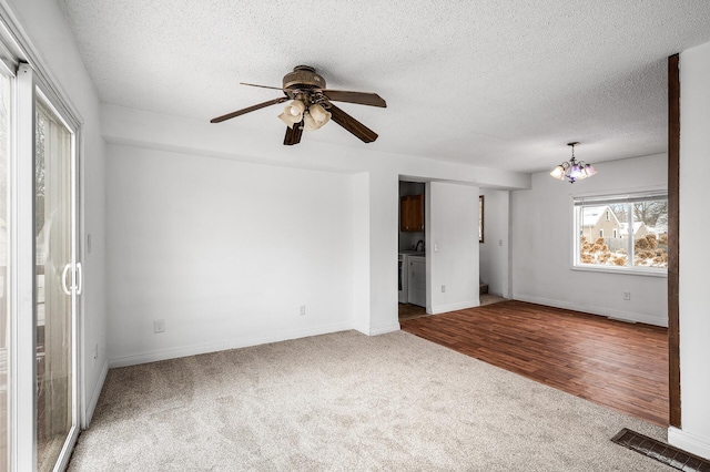 spare room featuring ceiling fan with notable chandelier, independent washer and dryer, a textured ceiling, and carpet