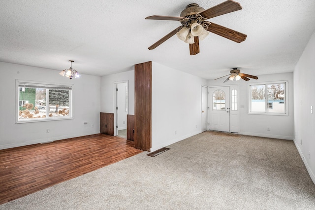 unfurnished living room featuring light colored carpet, a chandelier, and a textured ceiling