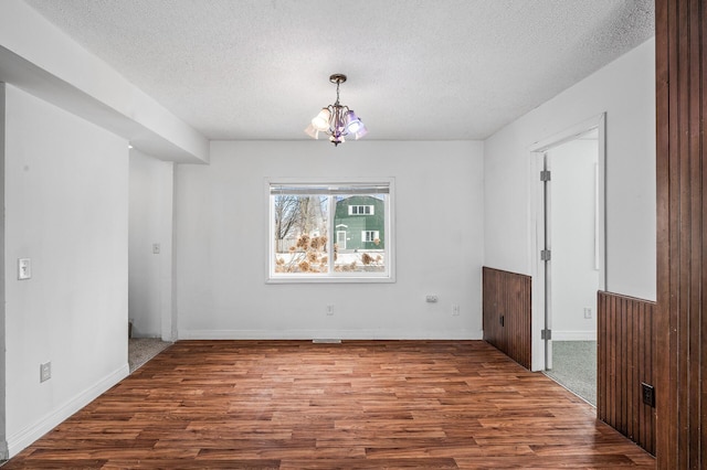 spare room with wood-type flooring, a chandelier, and a textured ceiling