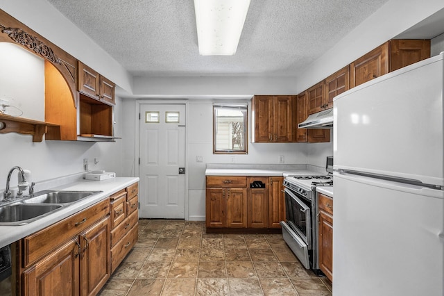 kitchen with sink, dishwashing machine, white refrigerator, gas range, and a textured ceiling