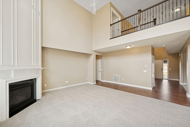 5270 Jewel Ln N, Plymouth, MN 55446 - unfurnished living room featuring carpet, a towering ceiling, baseboards, a fireplace, and wood finished floors