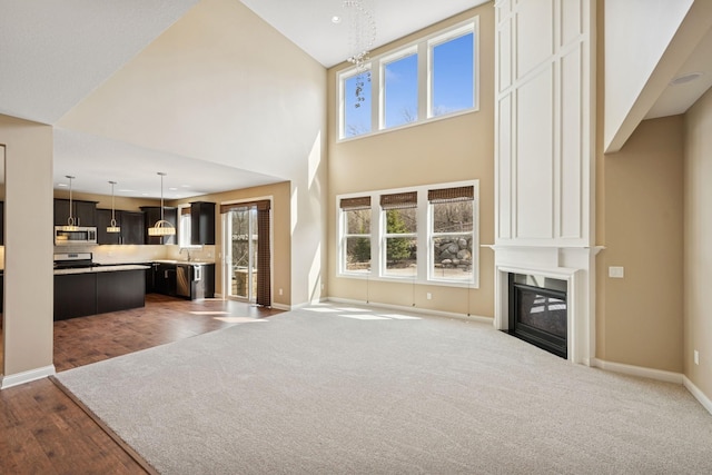 5270 Jewel Ln N, Plymouth, MN 55446 - unfurnished living room featuring baseboards, a fireplace, a towering ceiling, dark carpet, and a chandelier