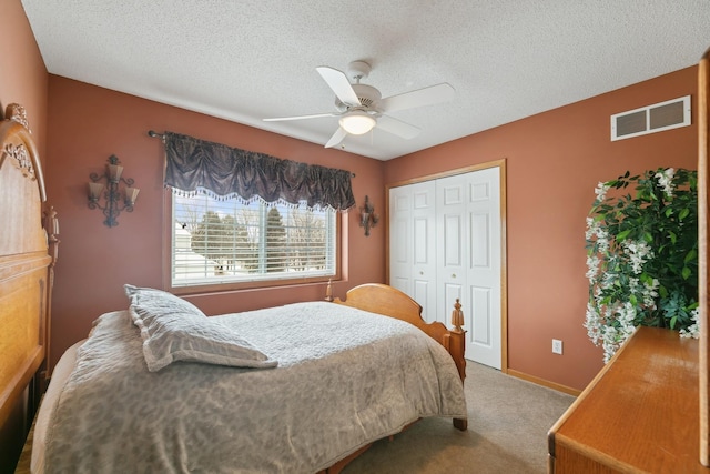 carpeted bedroom with ceiling fan, a closet, and a textured ceiling