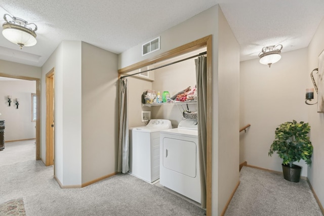 laundry room with washing machine and clothes dryer, light carpet, and a textured ceiling