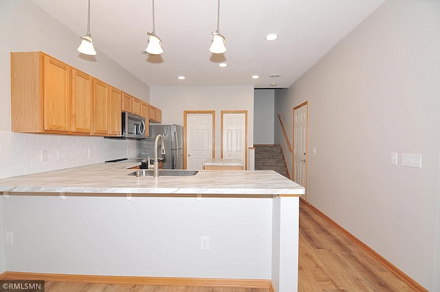 kitchen with hanging light fixtures, a kitchen breakfast bar, kitchen peninsula, stainless steel appliances, and decorative backsplash