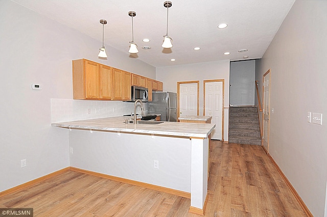 kitchen with stainless steel appliances, sink, pendant lighting, and kitchen peninsula