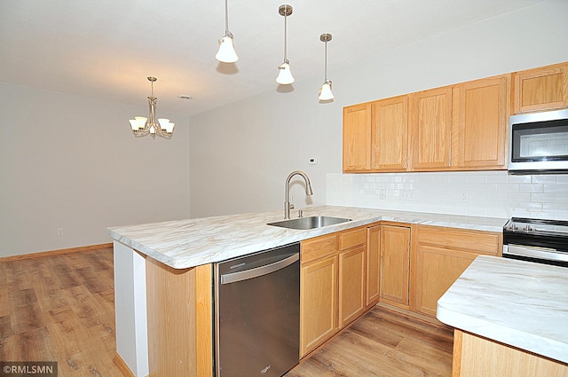 kitchen featuring stainless steel appliances, decorative light fixtures, sink, and light wood-type flooring