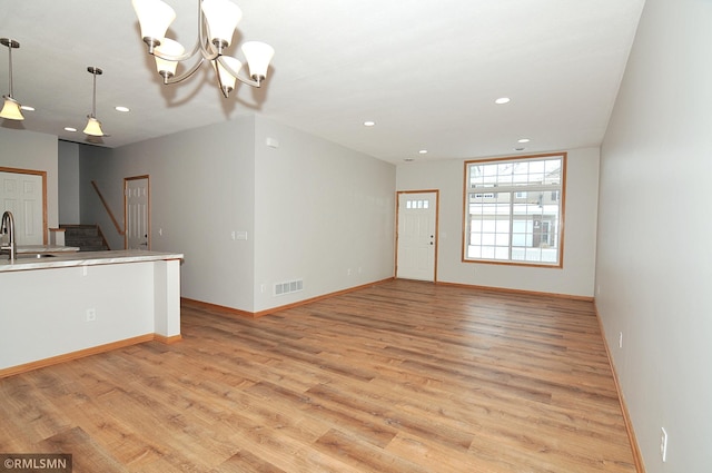 unfurnished living room with a chandelier, light hardwood / wood-style floors, and sink