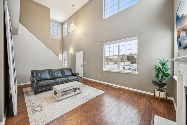 living room with a premium fireplace, dark hardwood / wood-style floors, a chandelier, and a healthy amount of sunlight