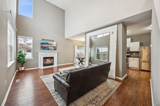 living room with dark wood-type flooring and a towering ceiling