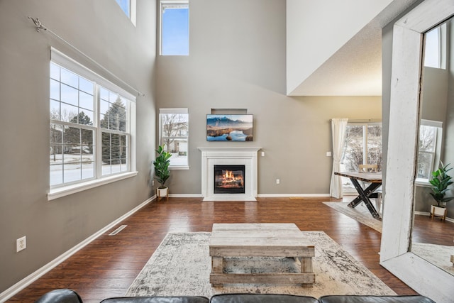 unfurnished living room featuring dark hardwood / wood-style flooring, a wealth of natural light, and a high ceiling