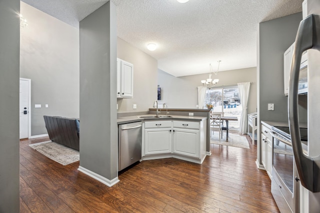 kitchen featuring pendant lighting, white cabinetry, dishwasher, sink, and kitchen peninsula