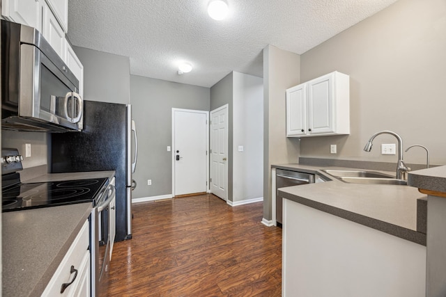 kitchen featuring appliances with stainless steel finishes, sink, white cabinets, dark hardwood / wood-style flooring, and a textured ceiling